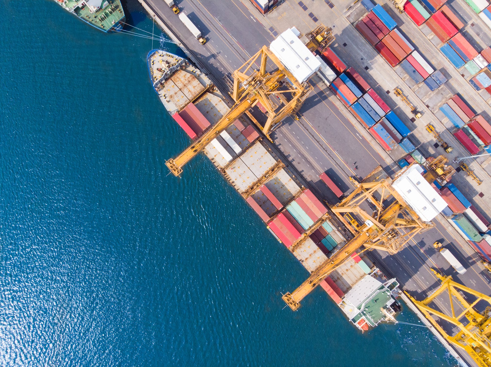 Top view Logistics and transportation of Container Cargo ship and Cargo plane with working crane bridge in shipyard at sunrise, logistic import export and transport industry background